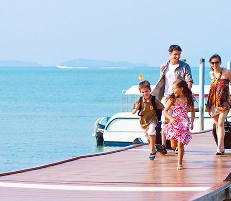 Family with suitcases walking down a pier away from a boat.