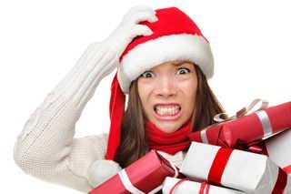 Christmas stress - busy woman wearing santa hat stressing for christmas shopping holding may christmas gifts in her arms. Funny image of multiracial Asian Caucasian female model isolated on white background.
