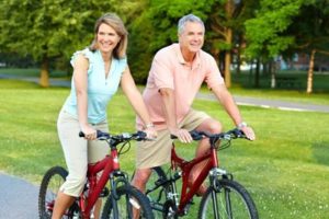 Happy elderly senior couple cycling in park