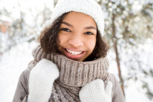 Portrait of teenage African American girl wearing warm clothing walking, looking at camera and laughing in winter