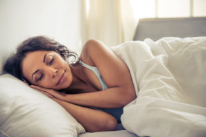 Side view of beautiful young African American woman smiling while sleeping in her bed at home