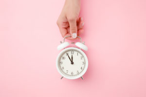 alarm clock sleep with hand on pink background