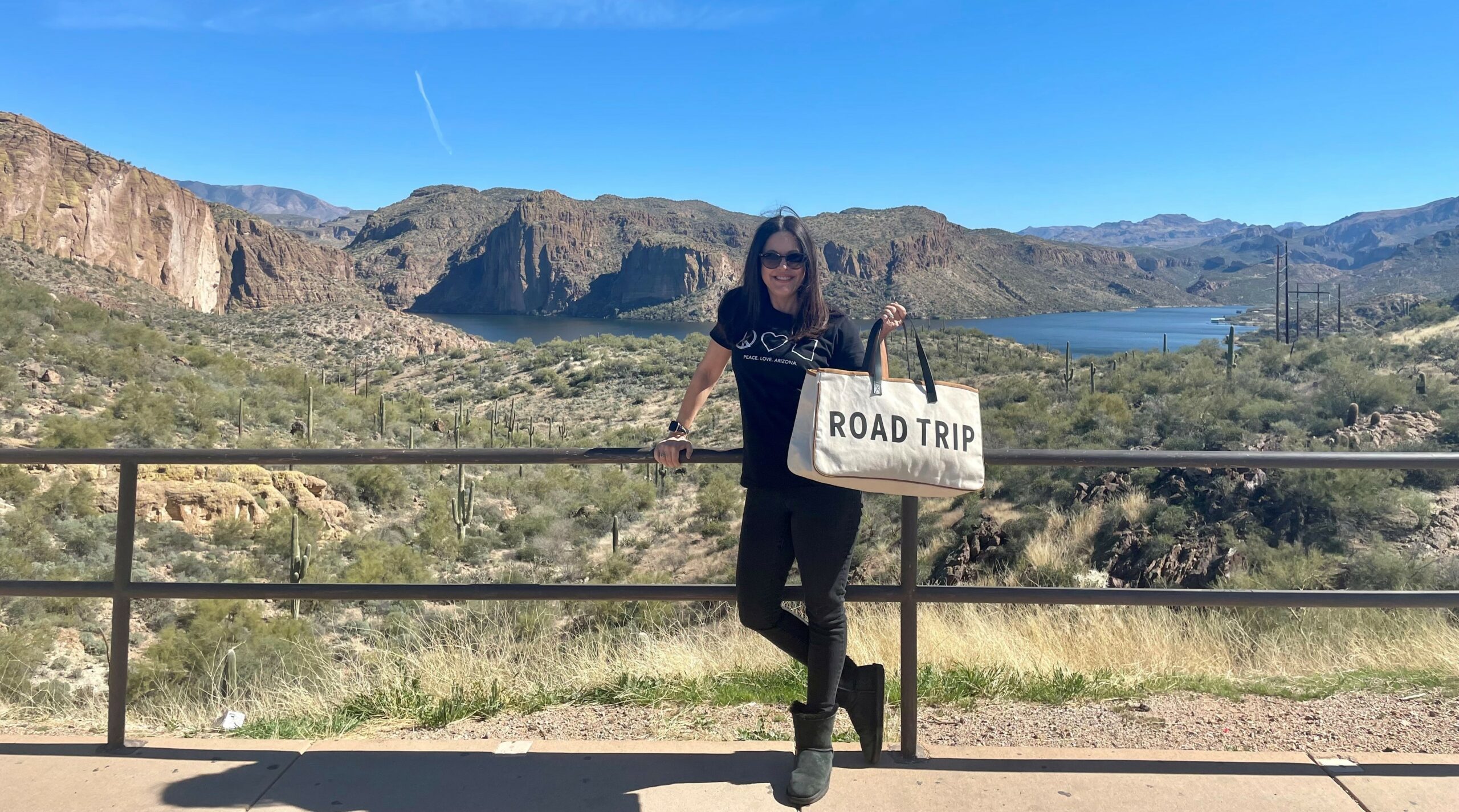 Rachel Harris holding a Road Trip bag and standing in front of a beautiful view.