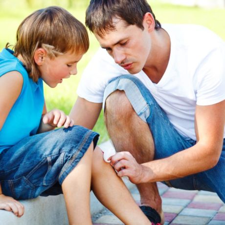 A father putting a bandage on his child's scrape.