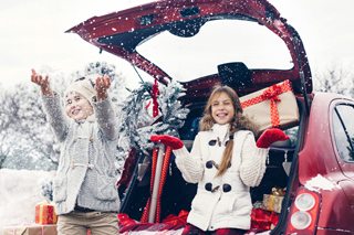 Pre teen children enjoy many Christmas presents in car trunk. Cold winter, snow weather.
