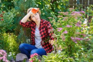 portrait of tired young woman gardener in garden. People, gardening, care of flowers, hobby concept