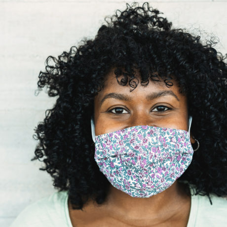 Happy black girl smiling under protective face mask - Young millennial person during coronavirus lifestyle - Health care and happiness concept - Focus on face