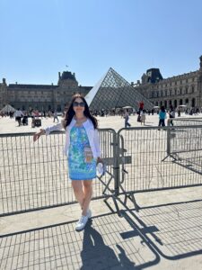 Rachel Harris standing outside The Louvre Pyramid.